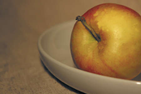 an apple on a plate against light backgroundの写真素材