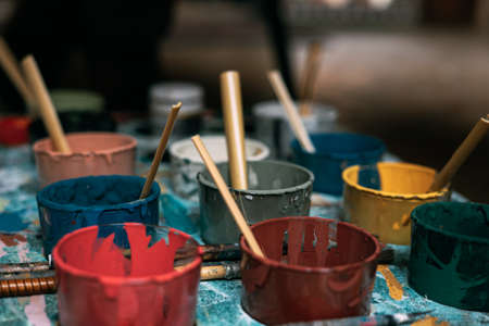 Brushes inside jars with different colours of paintの写真素材