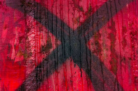 black cross painted on worn  red backgroundの写真素材