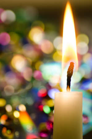 Christmas candle over colorful lights backgroundの写真素材