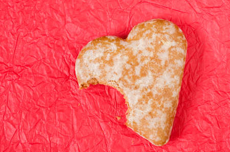 gingerbread heart cookie on red paper table backgroundの写真素材