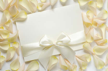 empty white card with ribbon on roses petals backgroundの写真素材
