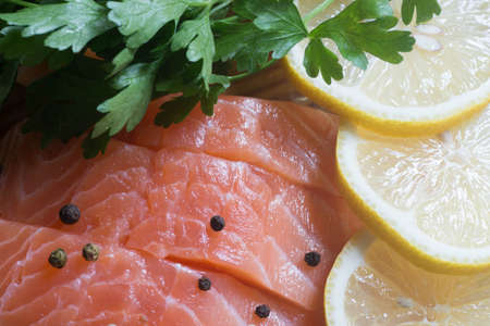 raw salmon with parsley, pepper and lemon on wooden tableの写真素材