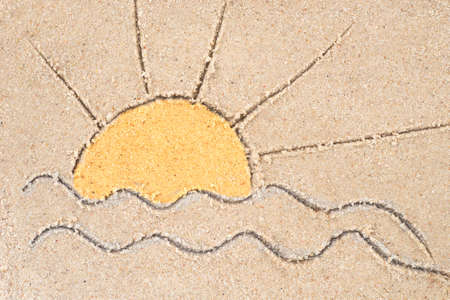 sunrise over sea drawing in sand backgroundの写真素材