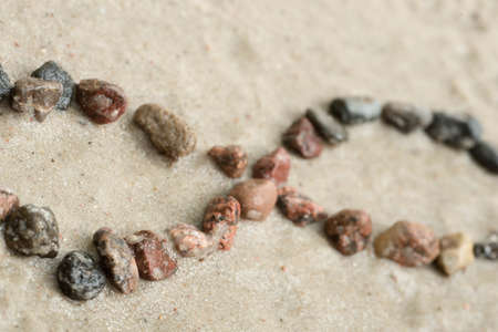 Pebble infinity symbol on sand background selective focusの写真素材