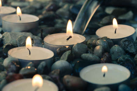 tea-light candles on pebbles stones selective focus closeup