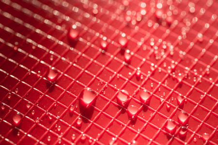 water drops on red color plastic background texture
