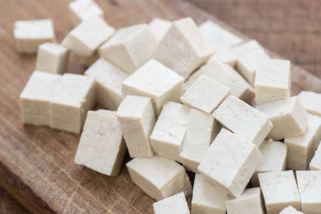 fresh tofu cubes on wooden cutting board macroの写真素材