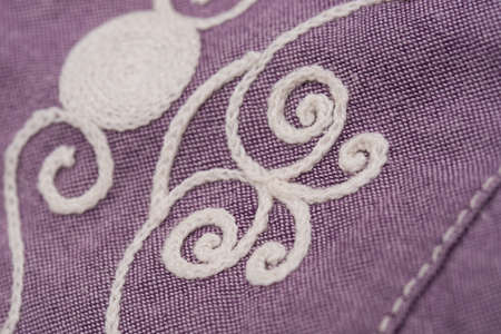 white embroidery on violet textile, dress detail