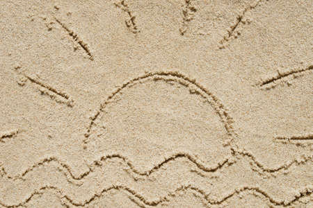 sun and waves written on sand top viewの写真素材