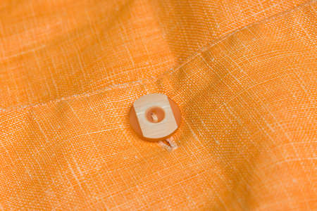 orange linen textile with button closeup