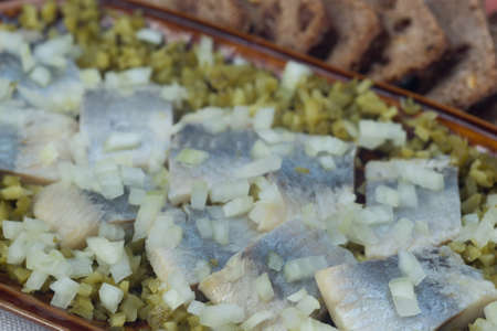 herring with onion and pickled cucumber on plate closeup selective focusの写真素材