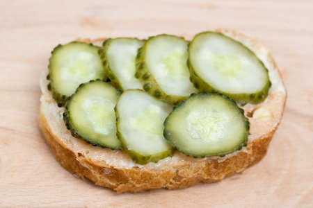 small open sandwich with spread and cucumber on wooden boardの写真素材