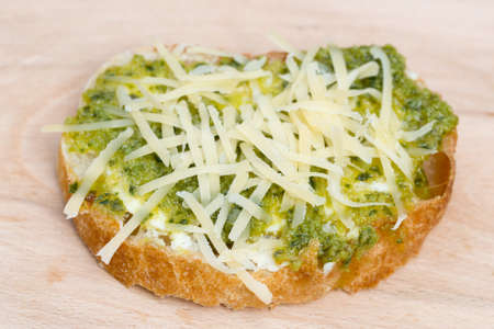 small open sandwich with vegetarian spread and grated cheese on wooden board selective focusの写真素材