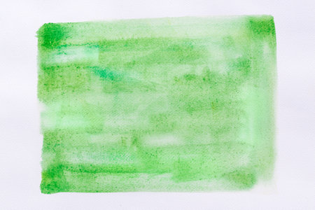 green painted watercolor background on white paper textureの写真素材