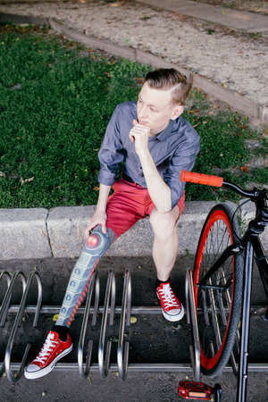 Hipster with red bycicle and tattoo on leg in parkの写真素材