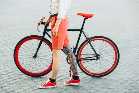 Hipster with red bycicle and tattoo on leg.の写真素材