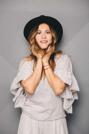 Young beautiful woman posing in white dress and black hat