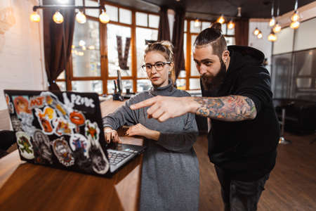 Man and woman discussing over digital laptop in creative officeの写真素材