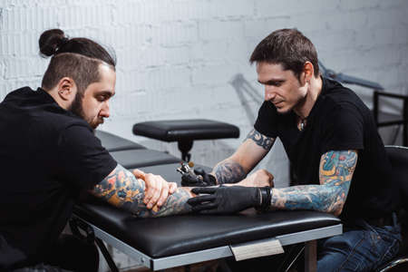 master tattooist makes a tattoo on the skin of the client with special equipment