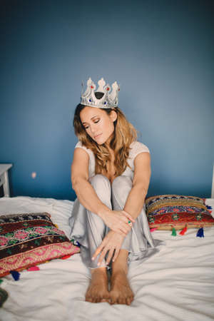 the girl with the crown lying on the bed in the house,の写真素材