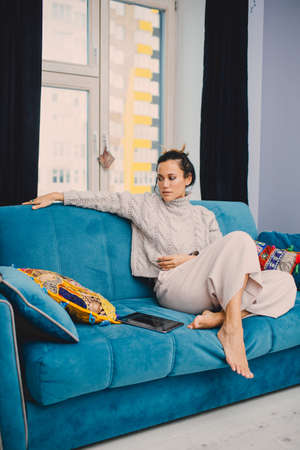 home, leisure and happiness concept - smiling teenage girl lying on sofaの写真素材