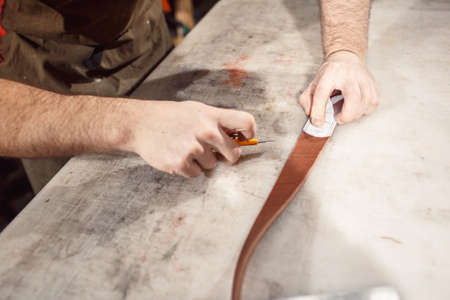 Close up of hands tanner performs work on table with tools