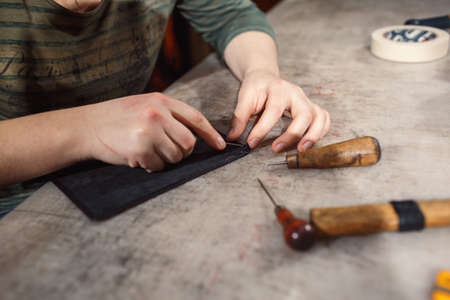 Close up of hands tanner performs work on table with tools