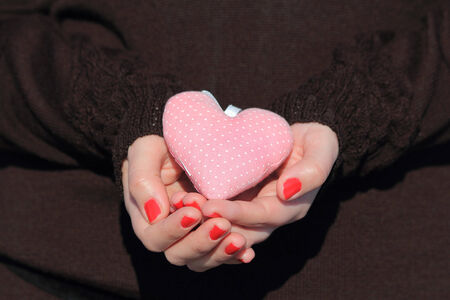 Hands holding a pink heart, black backgroundの写真素材