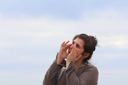 Young woman shouting, with hands on mouthの写真素材