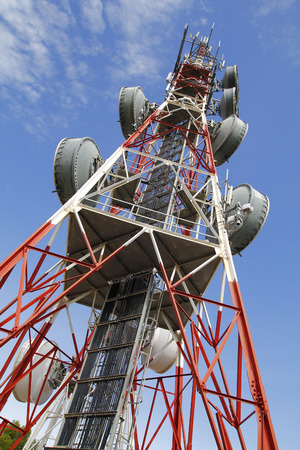 Telecommunications tower against blue sky, in red and whiteの写真素材