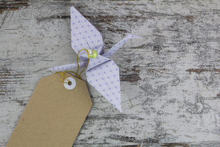 Origami stork with a tag, in a wood backgroundの写真素材