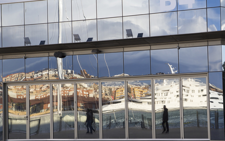 Reflected people in a building glass, walking in the harbor