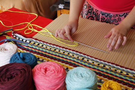 Woman hands weaving a handmade carpetの写真素材