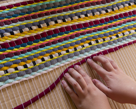 Woman hands weaving a handmade carpetの写真素材
