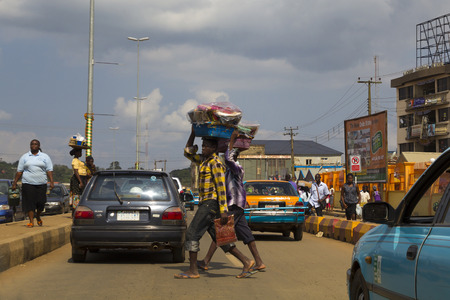 LAGOS, NIGERIA - AUGUST 12, 2012: Urban scene in Lagos, with many people trading, carrying goods over their head, in Lagos, Nigeria, on August 12, 2012のeditorial素材