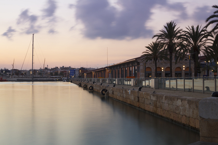 City view of Tarragona recreational harbor in the sunset, with lights reflected in the seaの写真素材