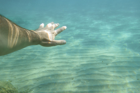 Human hand exploring underwater in clear seaのeditorial素材