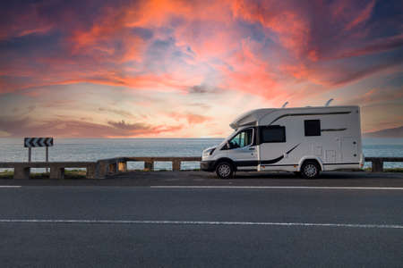 Caravan parked next to the sea at sunset, with dramatic skyの販売画像