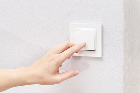 White electricity switch on a white wall. Turning on the lightの写真素材