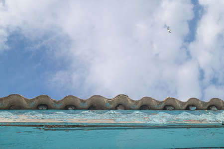The blue sky with clouds over the old slate roof of the houseの写真素材