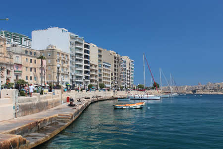 Seafront with people cars and boats in Sliema city bay, Malta. Saturated blue sky and azure sea.のeditorial素材