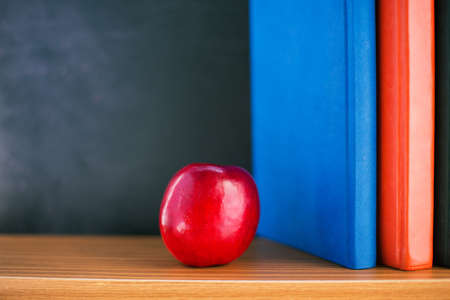 Red apple lying near books and blackboardの写真素材