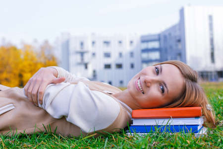 Student lying on the books and smiling at the cameraの写真素材