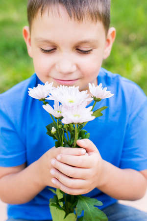 Boy holding flowers and smelling them. Selective focusの写真素材