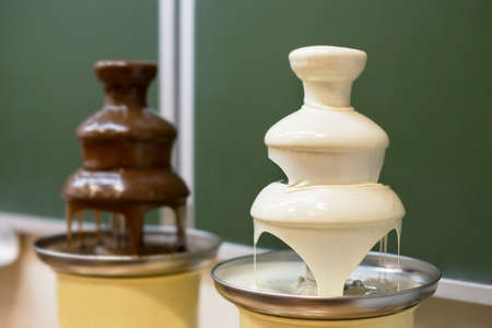 Two chocolate white and dark fondue fountains on school partyの写真素材