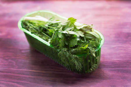 Fresh herbs in a transparent plastic containerの写真素材