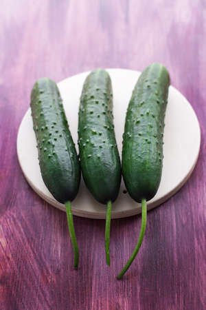 Three fresh cucumbers lying on a light plateの写真素材