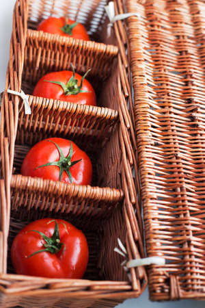 Four tomatoes lying separately in wicker boxの写真素材