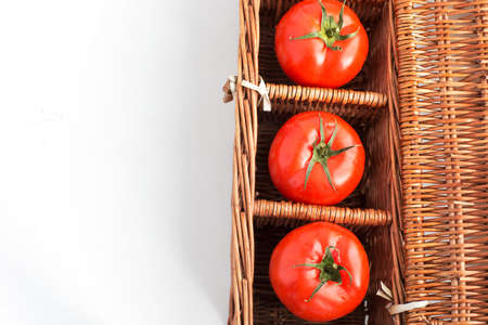 Three tomatoes in wicker box with copy spaceの写真素材